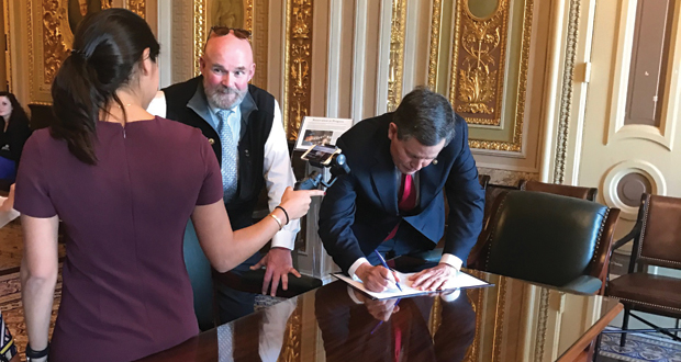 Steve Daines, the junior United States Senator from Montana, signs the Stop Online Booking Scams Act.