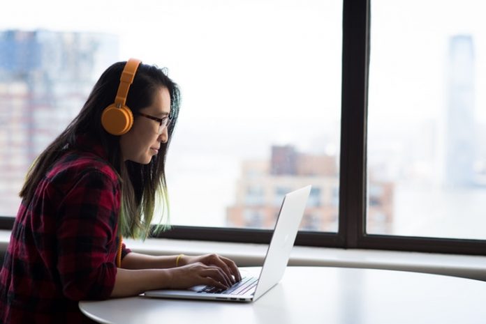 Woman using laptop and wearing headphones