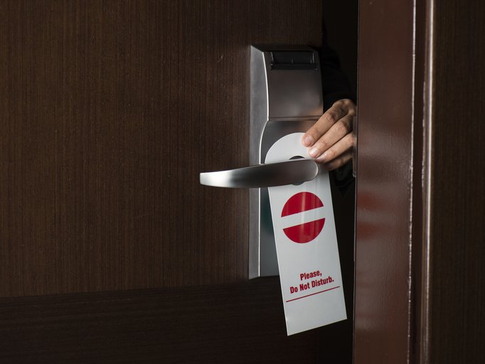 Hand hanging 'Do Not Disturb' sign on hotel door