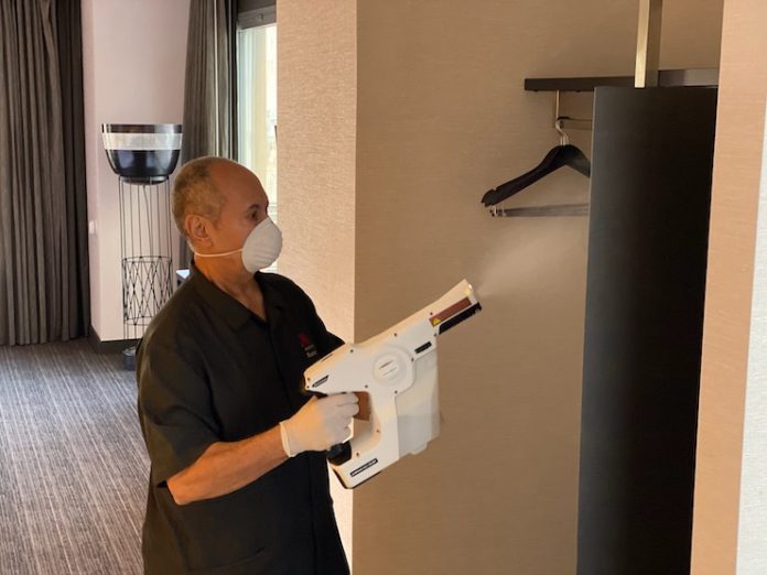 A Marriott International associate uses an electrostatic sprayer with hospital-grade disinfectant to sanitize surfaces.