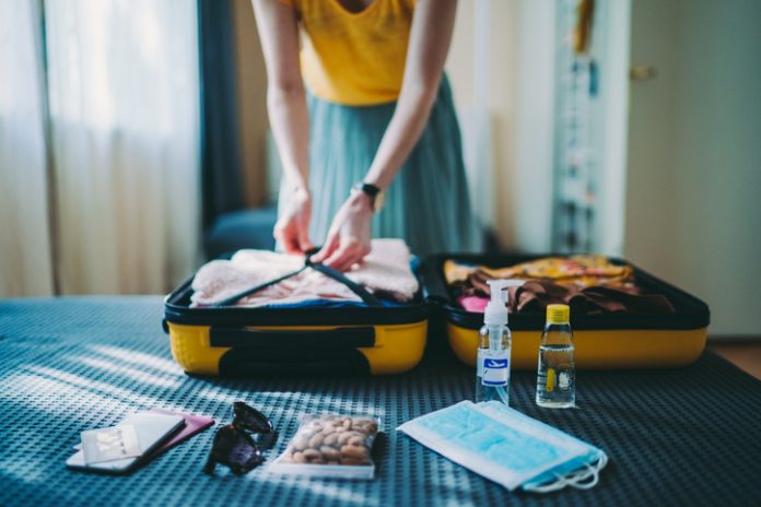 Traveler packing suitcase, including face coverings