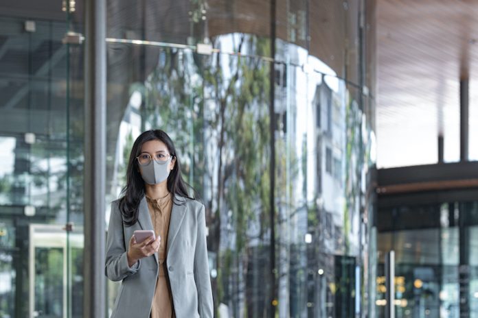 Woman wearing a face mask holding a phone