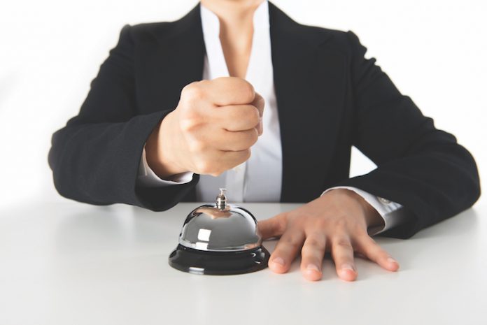 person holding a fist over a hotel front-desk bell