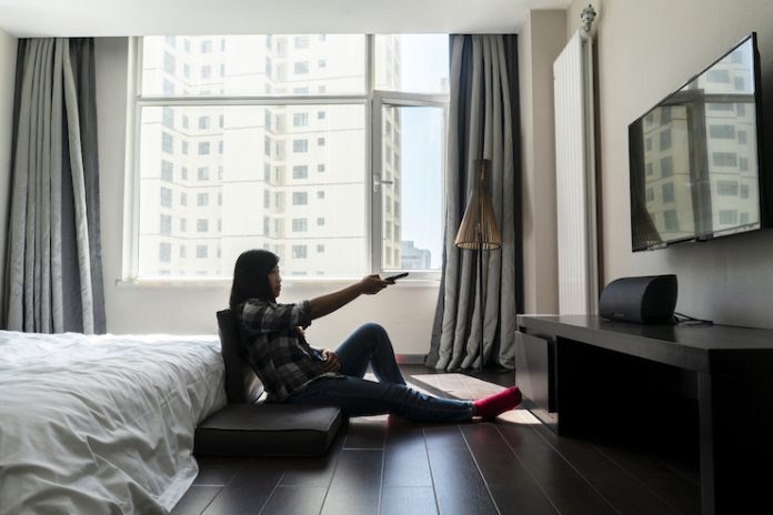 A woman watches TV in a hotel room