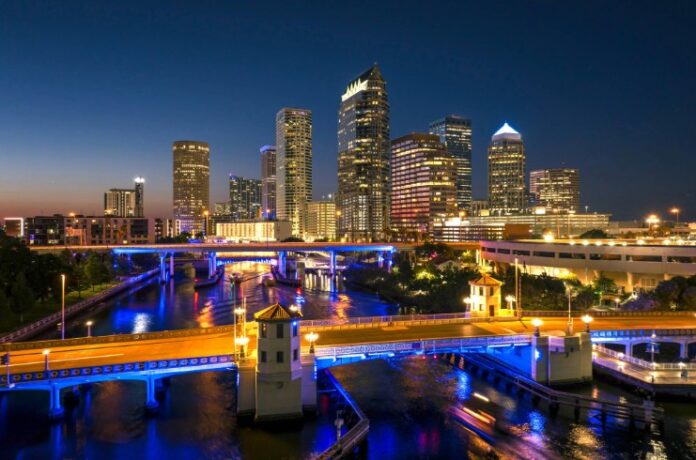 Tampa city in Florida with brightly illuminated highway traffic on bridge and skyscraper buildings in downtown district. American megapolis with business financial district at night Tampa stock